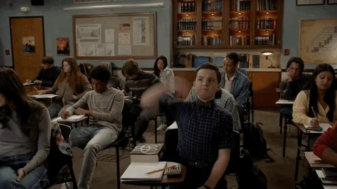 a guy in a school chair put up with hand